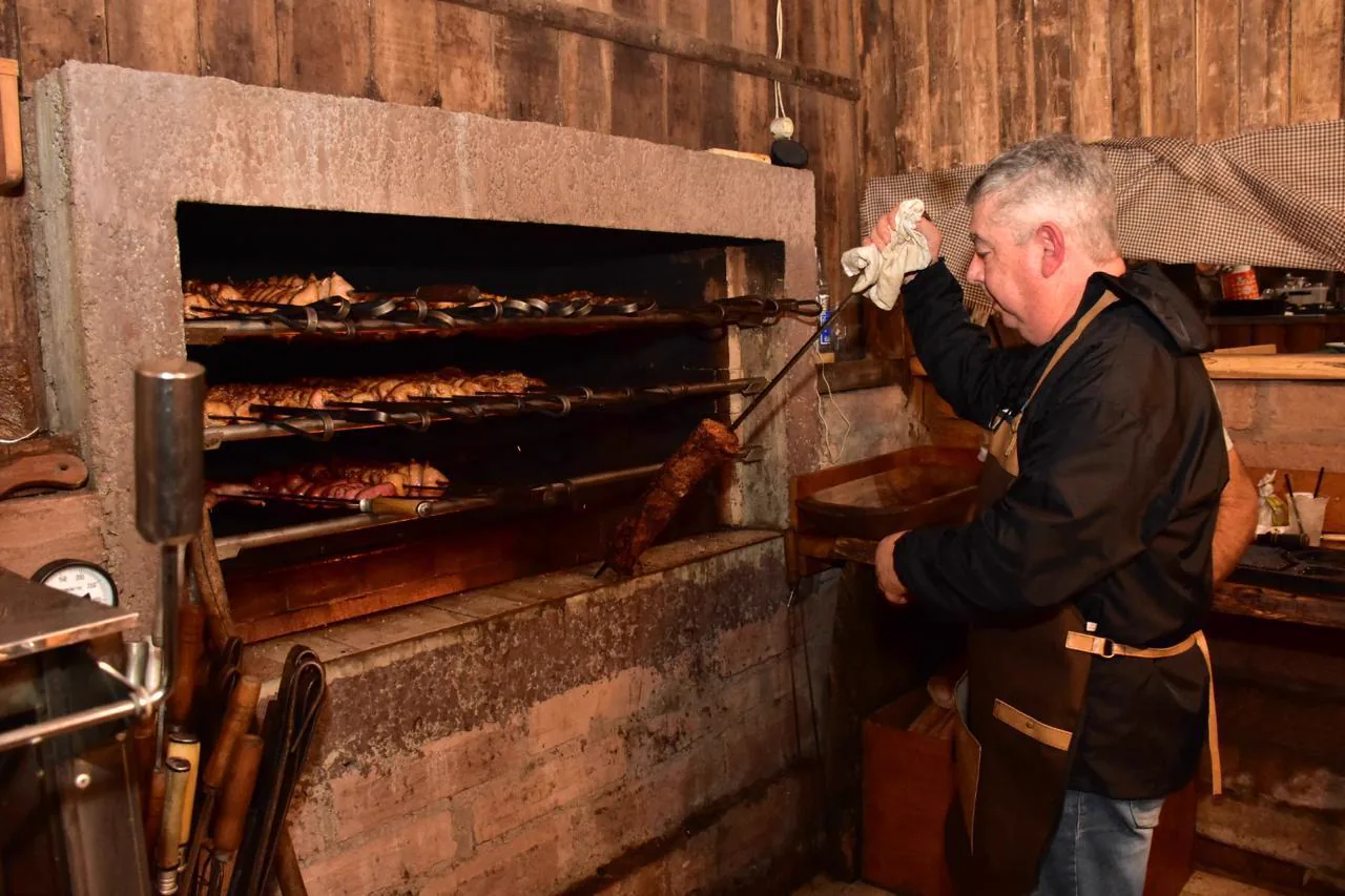 Assador preparando churrasco na churrasqueira rústica
