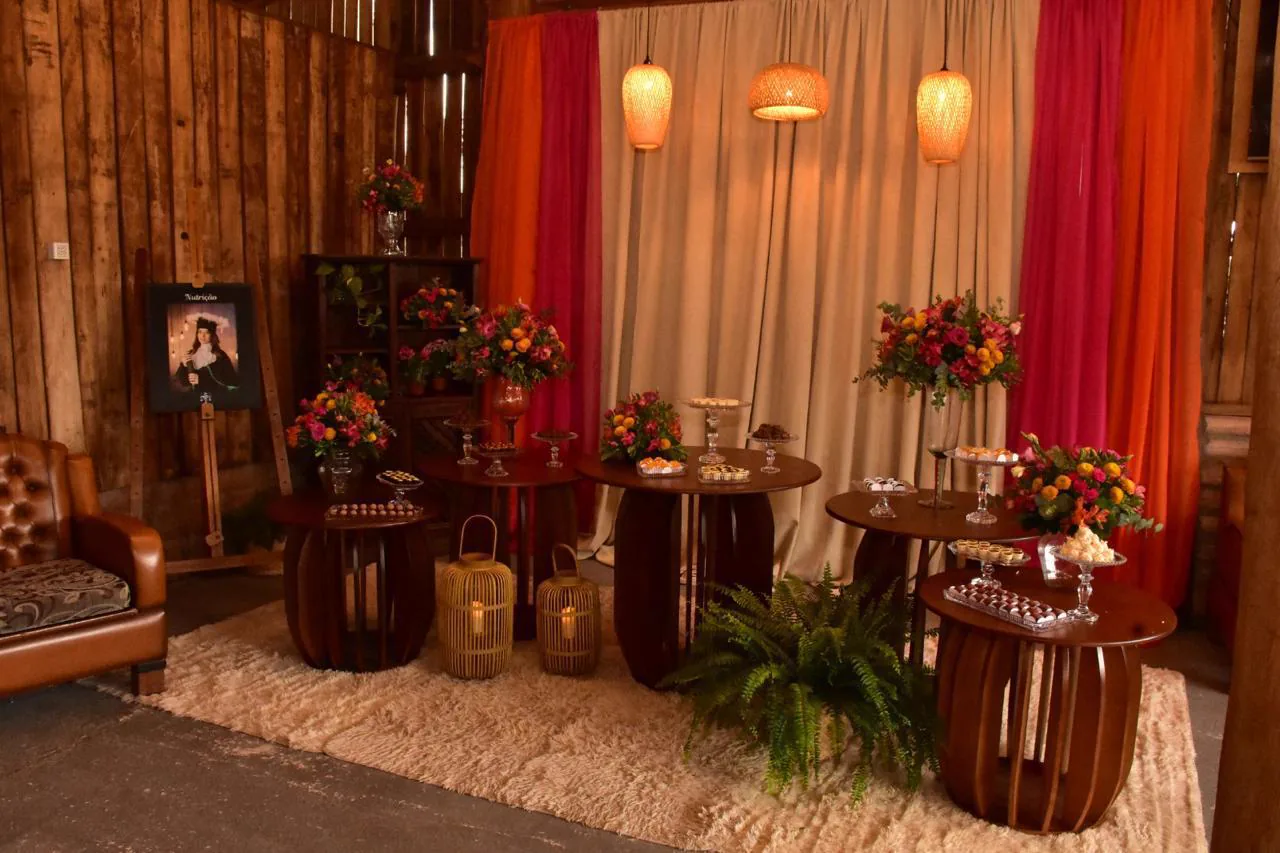 Mesa de bolos e doces com arranjos florais em uma celebração