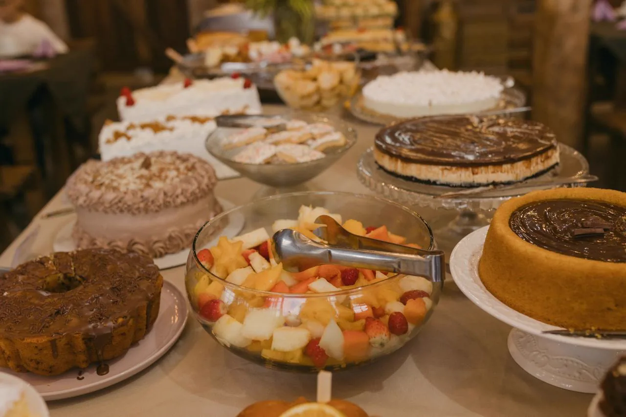 Mesa de sobremesas com bolos e frutas servidos na Aldeia